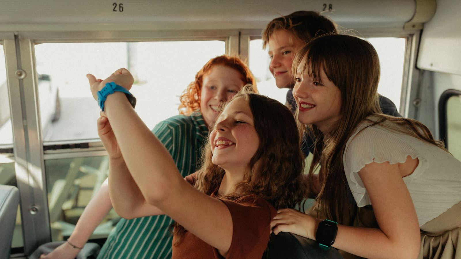 Kids on the school bus crowding around a friend's watch